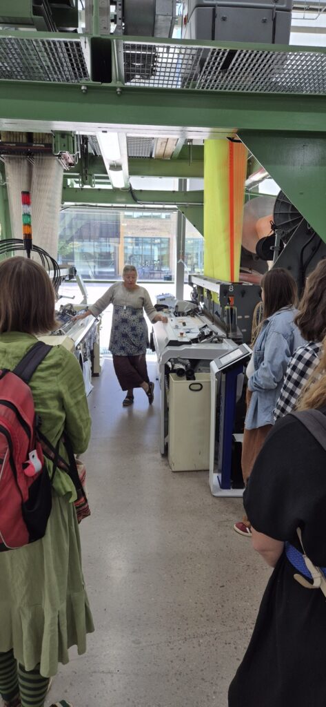 Gruppen får en visning bland maskinerna i Textilhögskolans undervisningsmiljö.